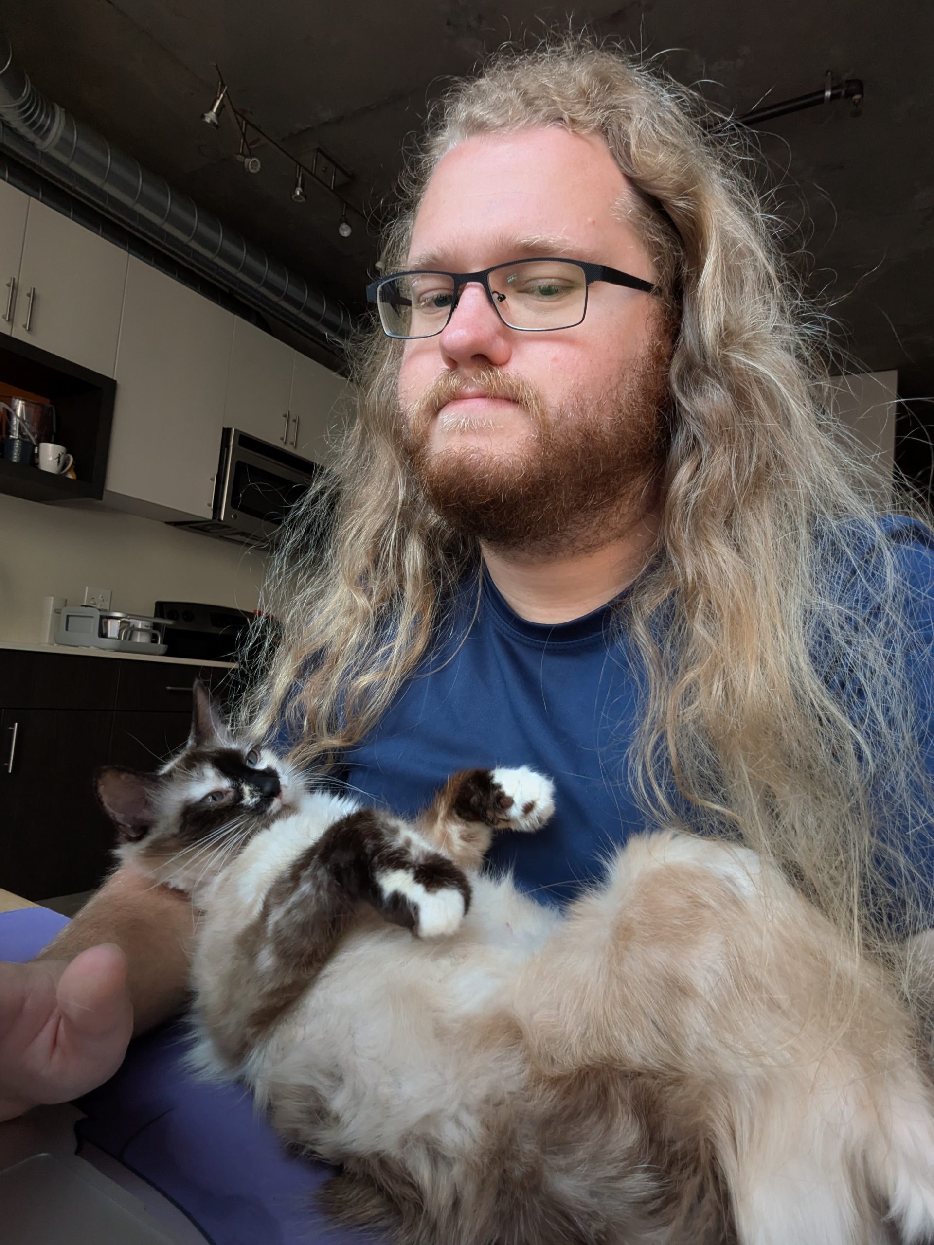 Ben sitting at the desk, Marshmallow laying in front of him on her back