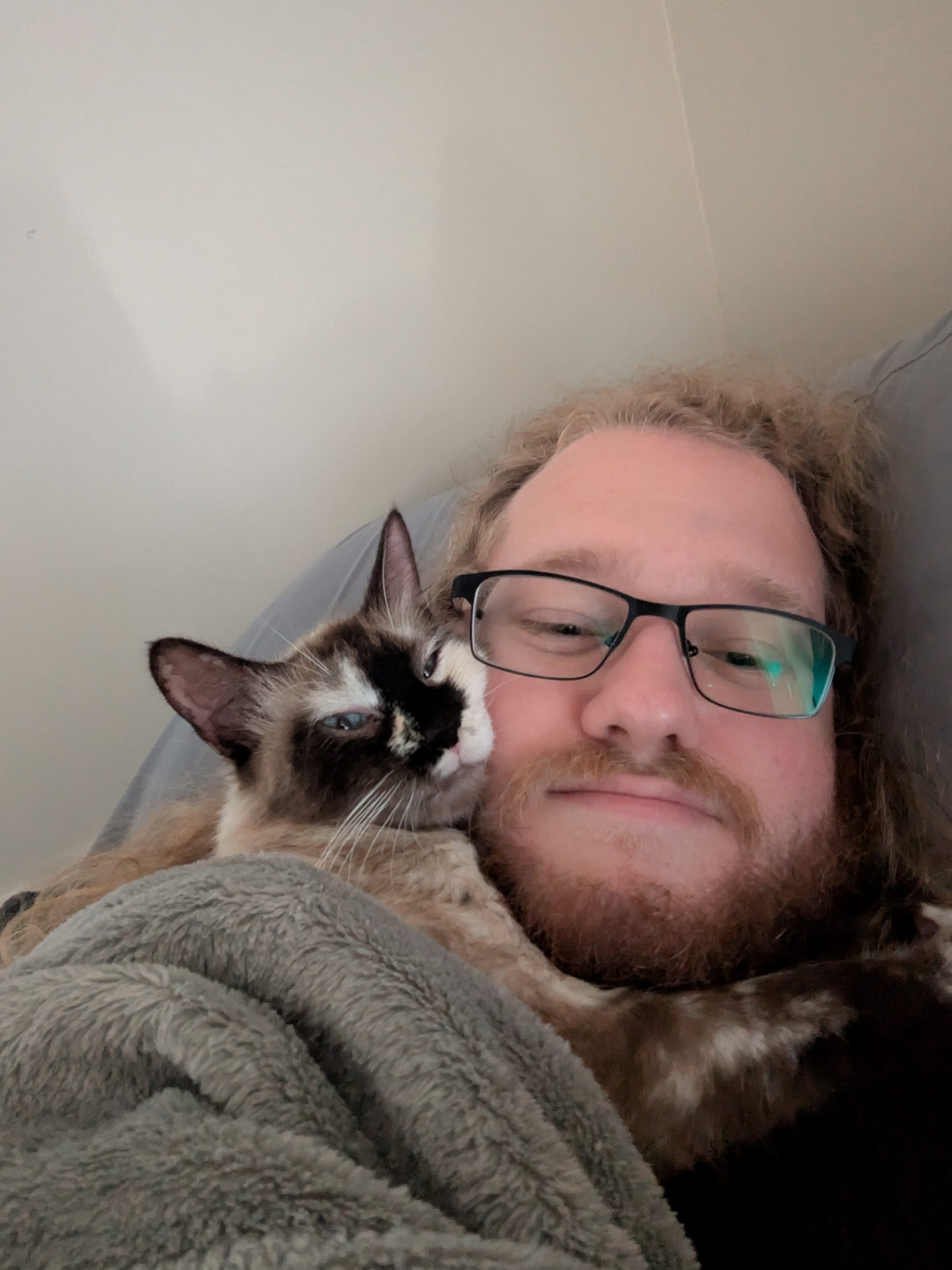 Ben laying down and Marshmallow smooshing her face against his